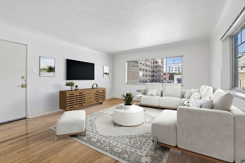 A living room with a white couch, a white chair, a wooden cabinet, and a flat screen TV.
