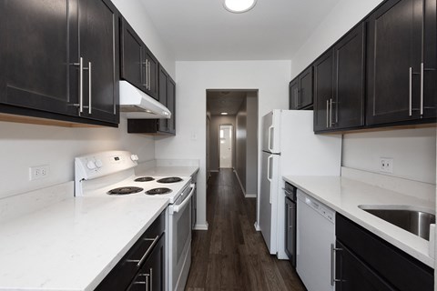a kitchen with white countertops and black cabinets and white appliances