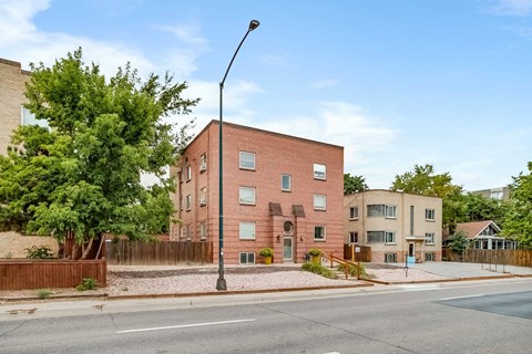 A street view of a residential area with a red brick building on the corner.