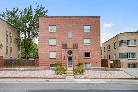 A red brick building with a small garden in front.