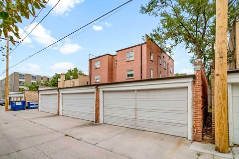 A row of garages in front of a red brick building.