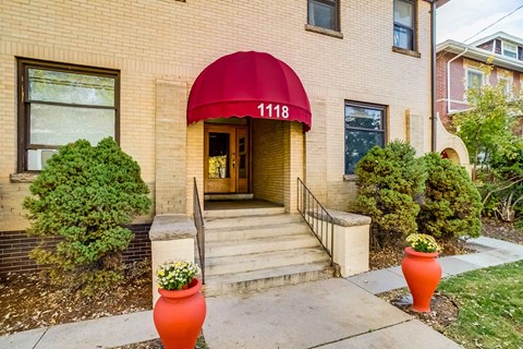 A red awning with the number 1118 on it is above the door of a brick building.