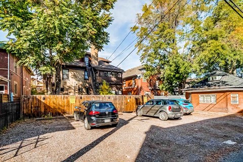 Two cars are parked in a gravel driveway in front of a house.