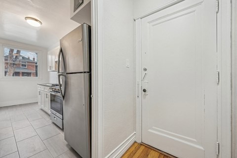 A kitchen with a stainless steel refrigerator and white cabinets.