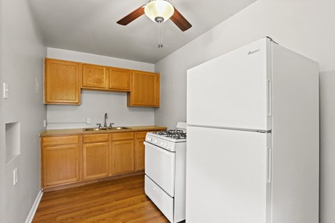 an empty kitchen with white appliances and wooden cabinets