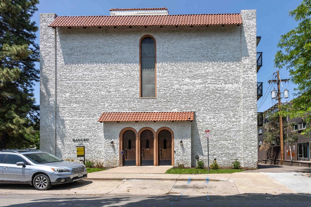 a church with a large window and a car parked in front of it