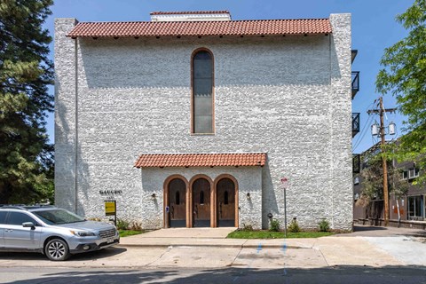 a church with a large window and a car parked in front of it