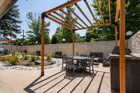 a patio with a table and chairs and a grill