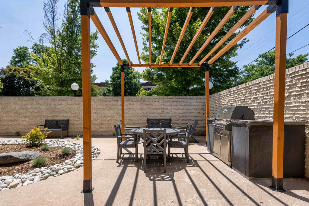 a patio with a table and chairs and a grill