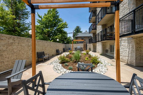 a patio with a table and chairs in front of a brick building