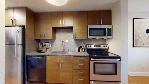 A kitchen with a refrigerator, oven, microwave, and sink.