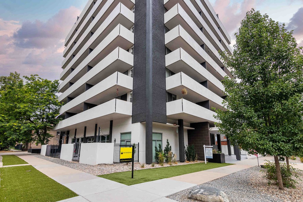 an apartment building with a sidewalk and trees in front of it