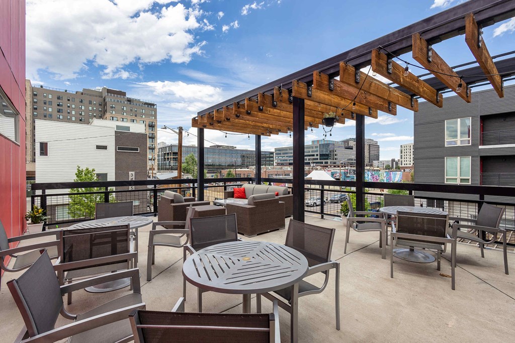 a rooftop patio with tables and chairs and a view of the city