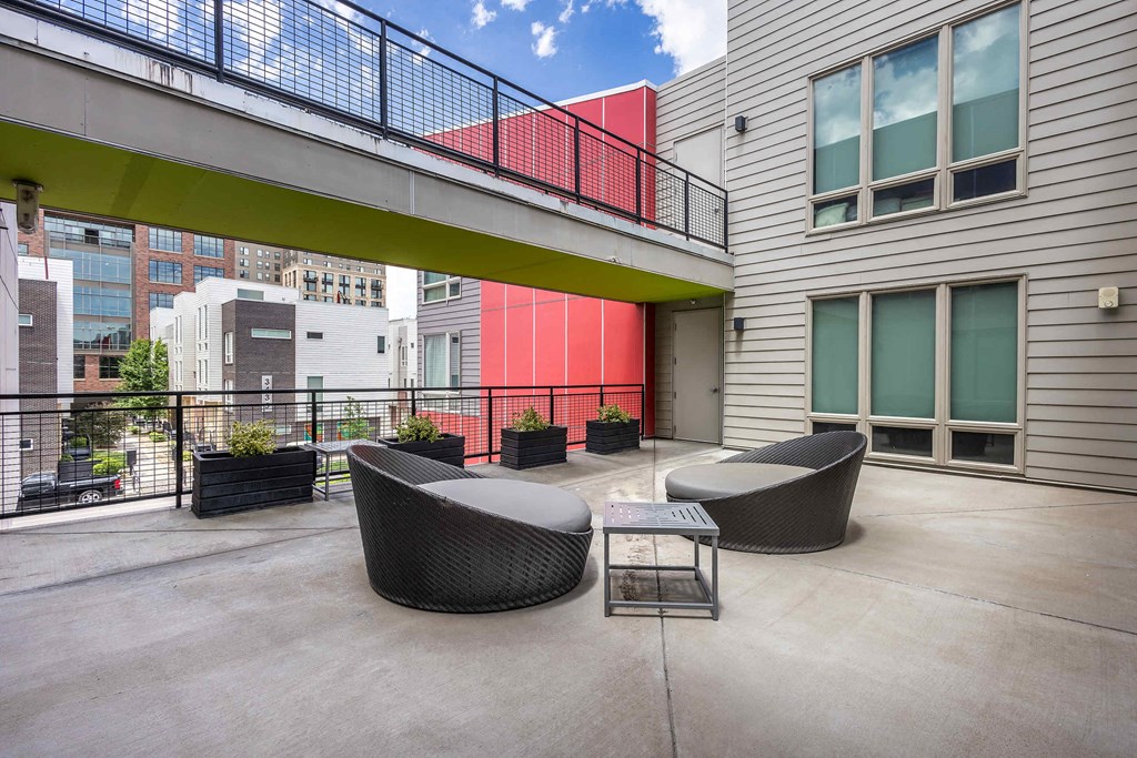 a patio with chairs and a table in front of a building