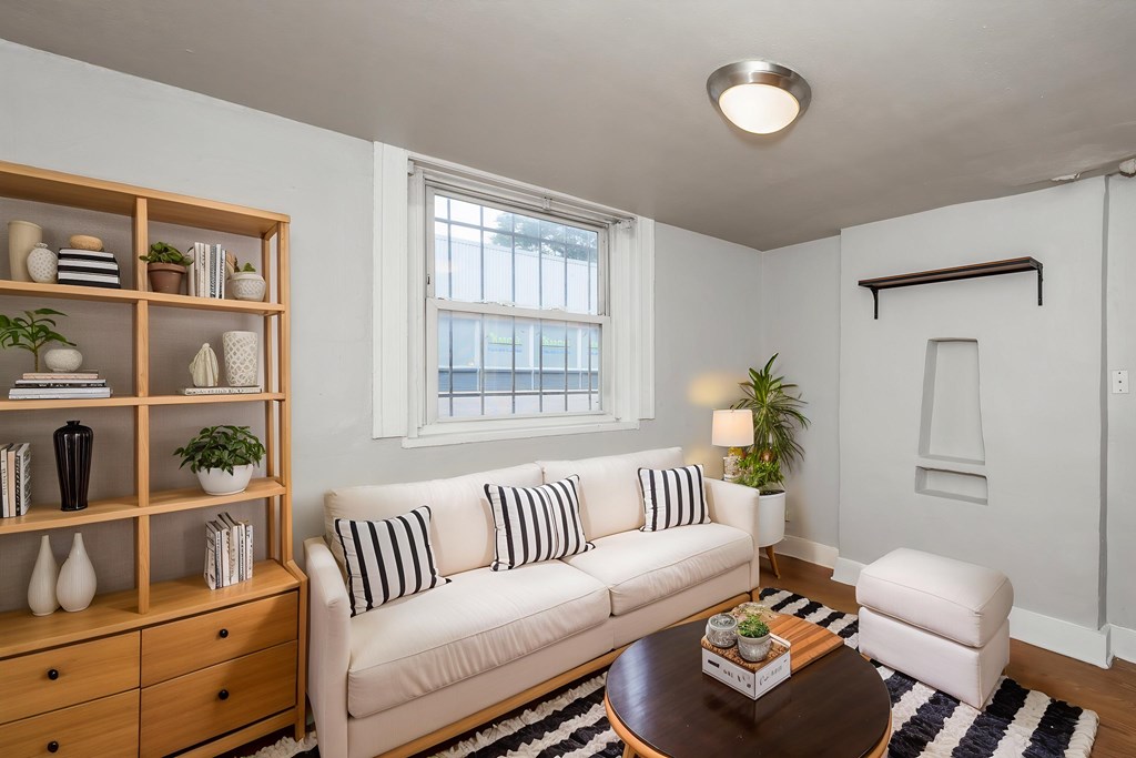 A living room with a white couch, a wooden shelf, and a coffee table.