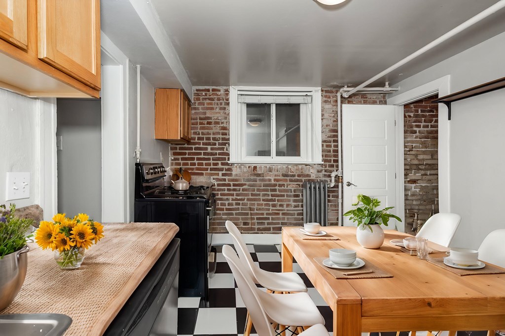A kitchen with a wooden table and chairs with a vase of flowers on it.