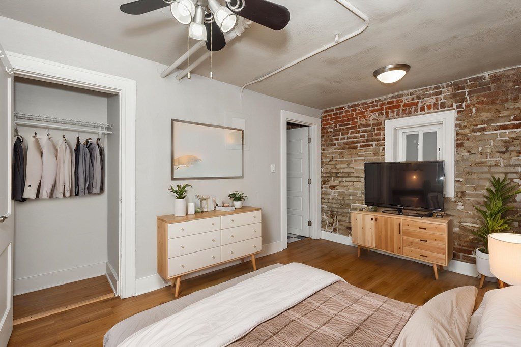 A bedroom with a bed, dresser, and a ceiling fan.