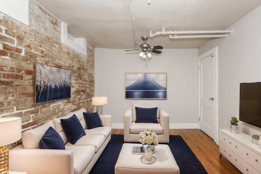 A living room with a white couch and a blue rug.