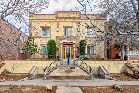 A brown brick building with a black railing on the steps.