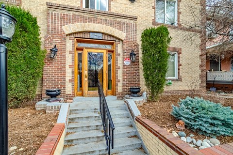 A house with a brown door and a brick wall.