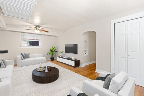 a living room with white furniture and a ceiling fan
