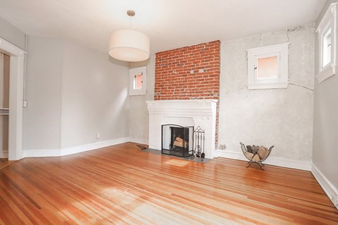 a living room with a brick fireplace and a wooden floor
