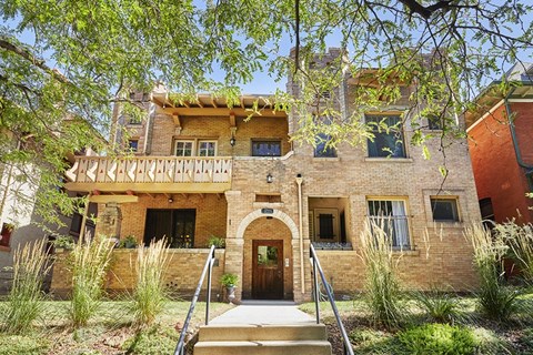 a brick building with a balcony and stairs in front of it
