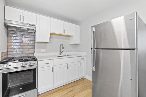 a renovated kitchen with stainless steel appliances and white cabinets