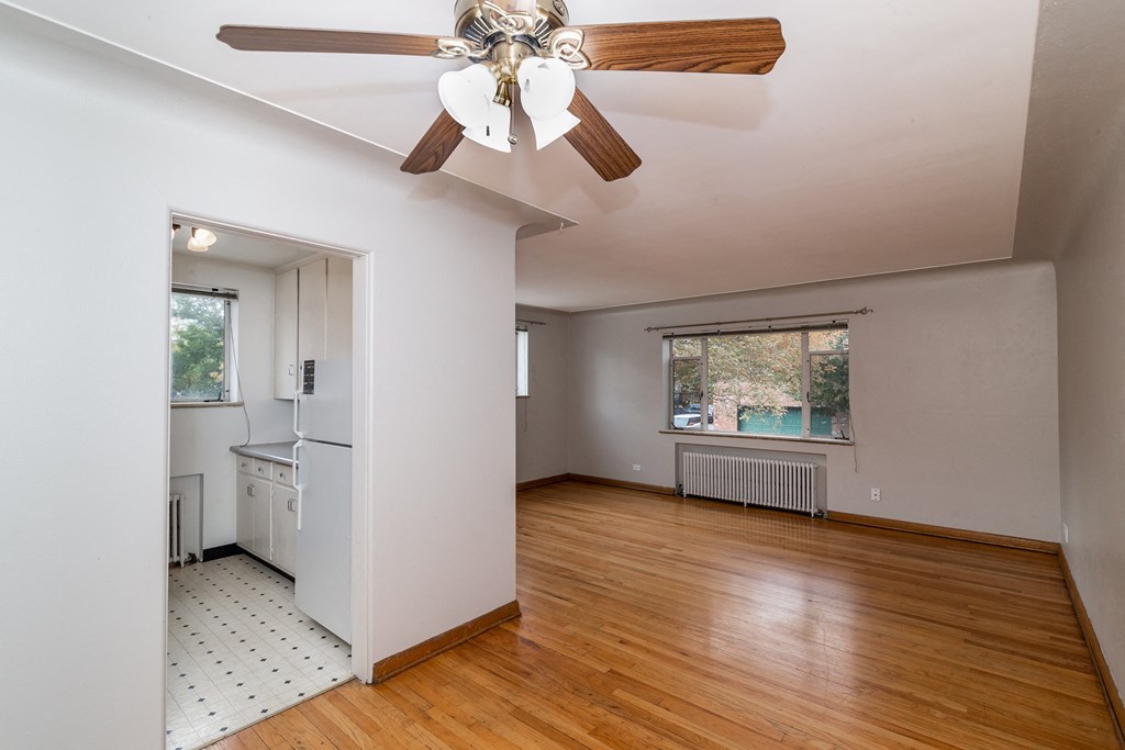A room with a ceiling fan and wooden floors.