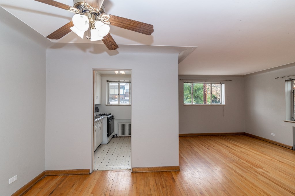 A room with a ceiling fan and wooden floors.