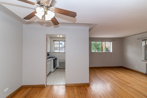 A room with a ceiling fan and wooden floors.