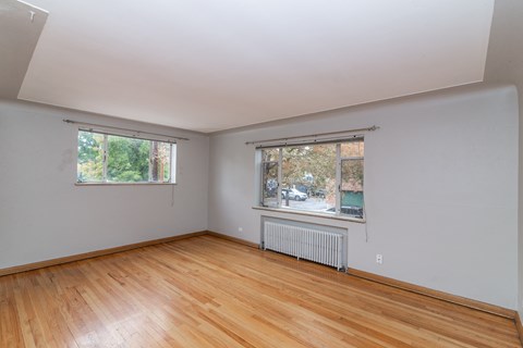A room with wooden floors and two windows.