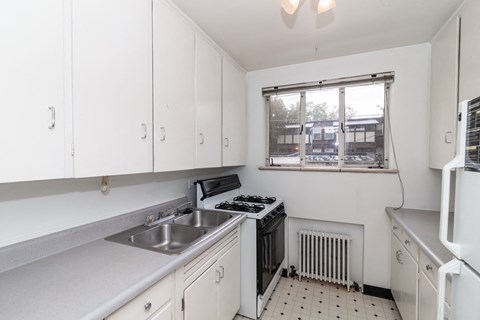 A white kitchen with a window overlooking a parking lot.