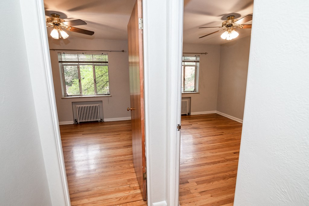 A room with a ceiling fan and wooden flooring.