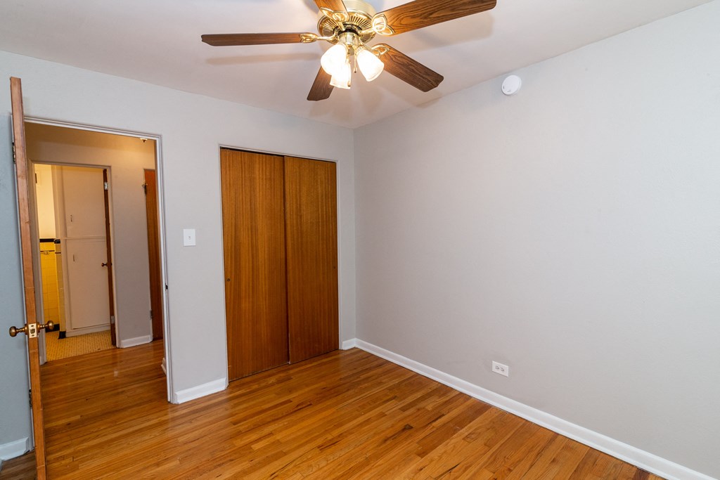 A room with a ceiling fan and wooden floors.
