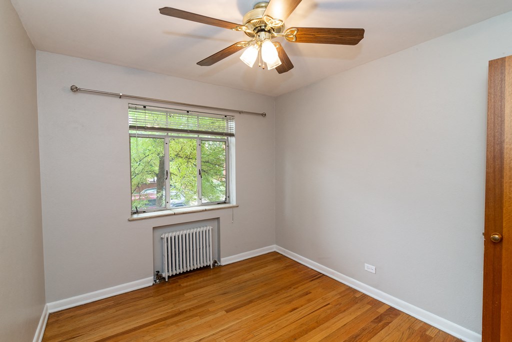A room with a ceiling fan and a window with blinds.