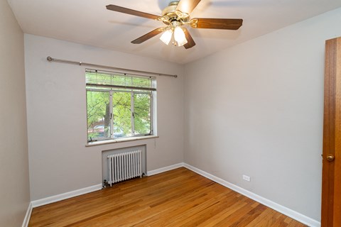 A room with a ceiling fan and a window with blinds.