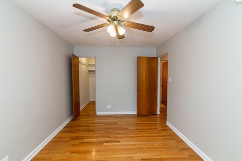 A room with a ceiling fan and wooden floors.