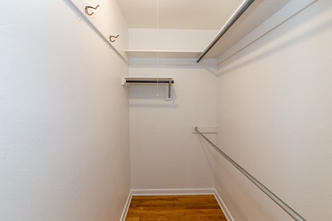 A white hallway with a wooden floor and a metal handrail.