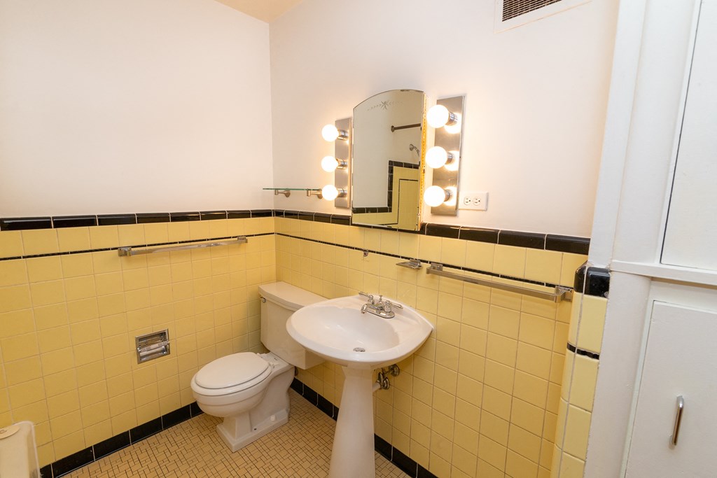A bathroom with yellow tiles and a white sink and toilet.