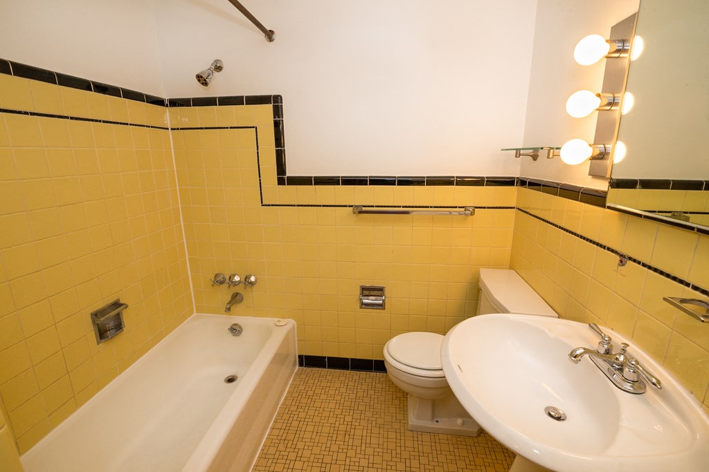A bathroom with yellow tiles and a white bathtub.