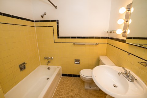A bathroom with yellow tiles and a white bathtub.