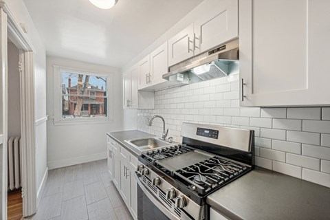 A kitchen with a stove top oven and a window.