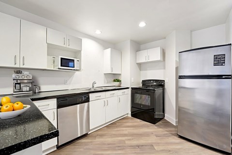 A kitchen with a black granite countertop and stainless steel appliances.