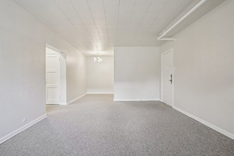 A large empty room with carpeted floor and white walls.