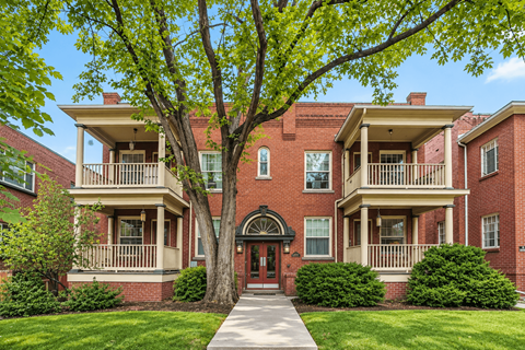 A red brick house with a tree in front.