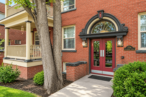 A red brick house with a tree in front.