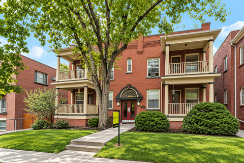 A red brick house with a tree in front.