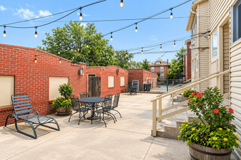 A patio with a table and chairs is surrounded by a brick wall.