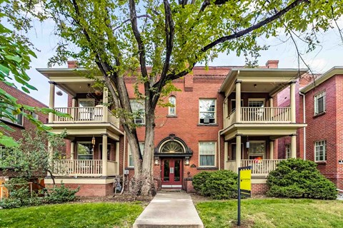 A red brick building with a tree in front.